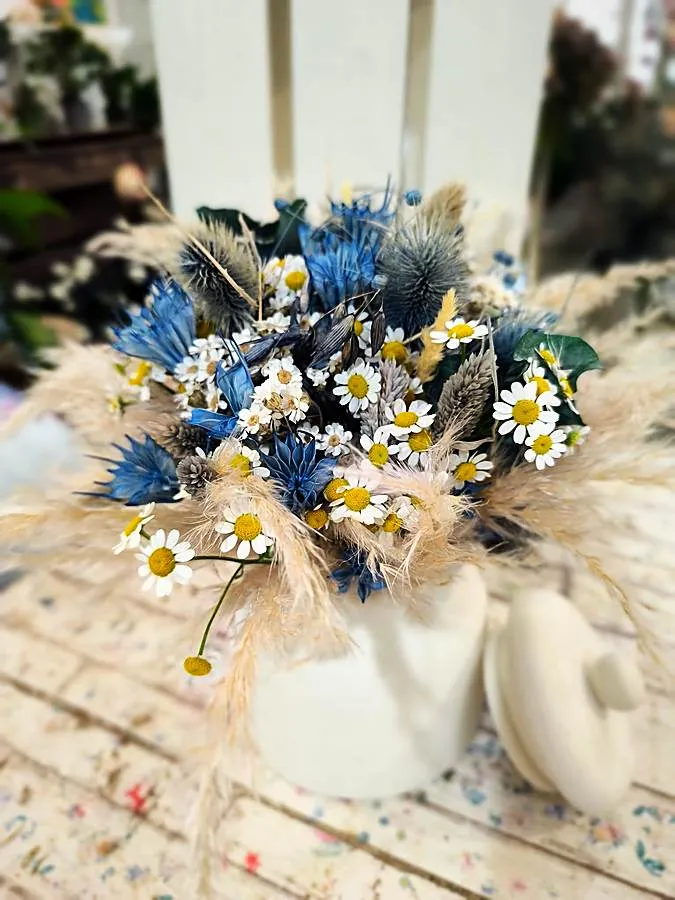 Bouquet di fiori secchi azzurri, margherite e pampas in una brocca bianca