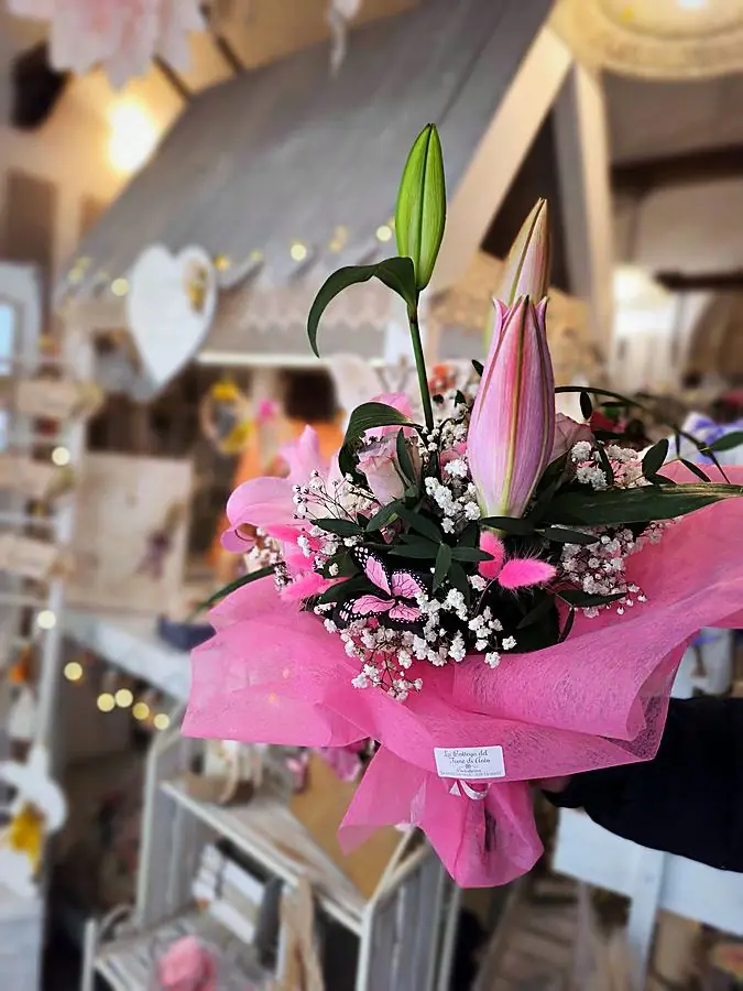 Bouquet di gigli rosa con farfalle decorative e carta rosa