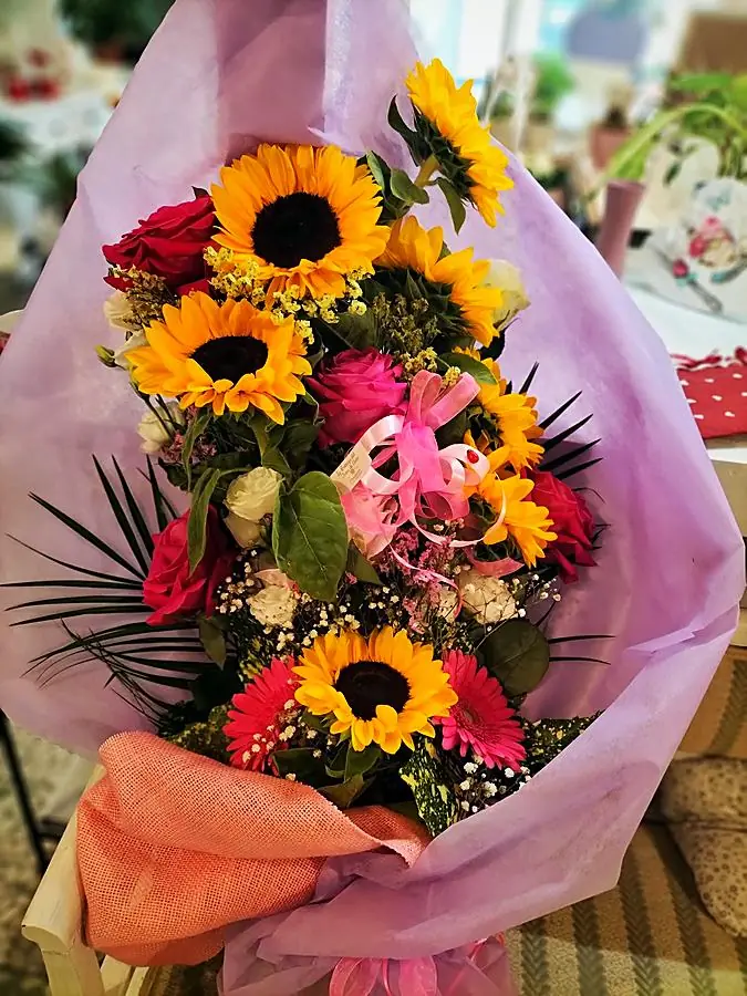Bouquet di girasoli, rose e gerbere avvolto in carta lilla
