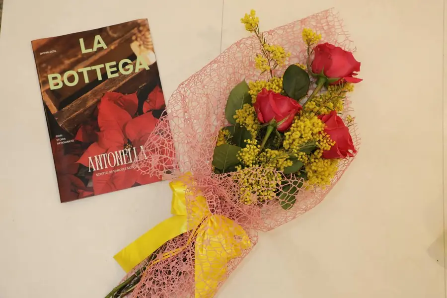 Bouquet di rose rosse e mimosa accanto alla rivista La Bottega
