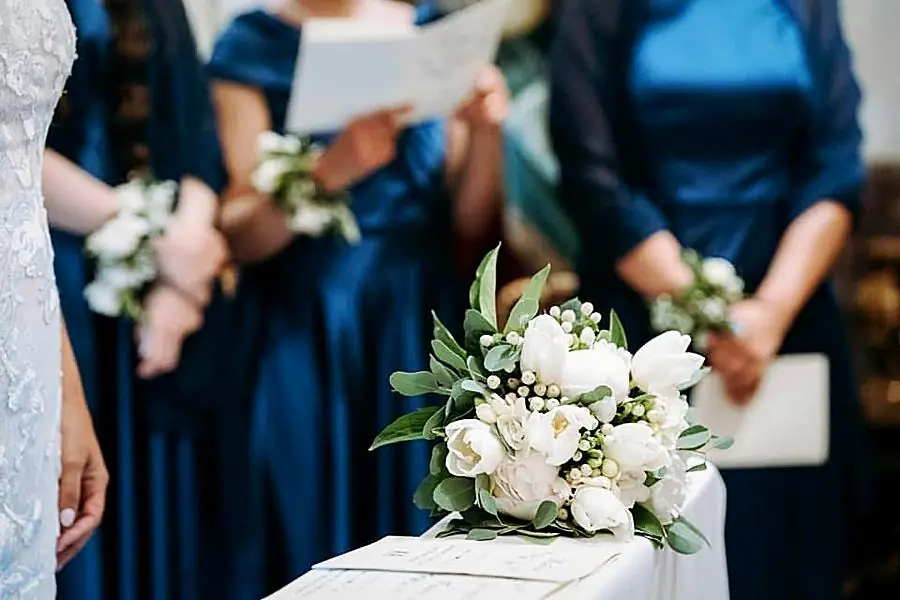 Bouquet di tulipani bianchi e bacche sul tavolo della cerimonia, con damigelle sfocate