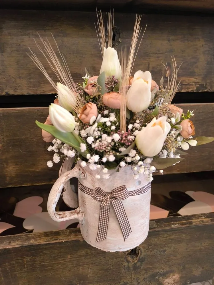Brocca bianca con tulipani, ranuncoli color cipria, gypsophila e spighe, con fiocco a quadretti marroni