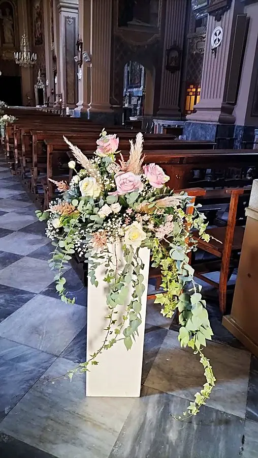Composizione di rose rosa, pampas ed edera cadente su colonna bianca in chiesa