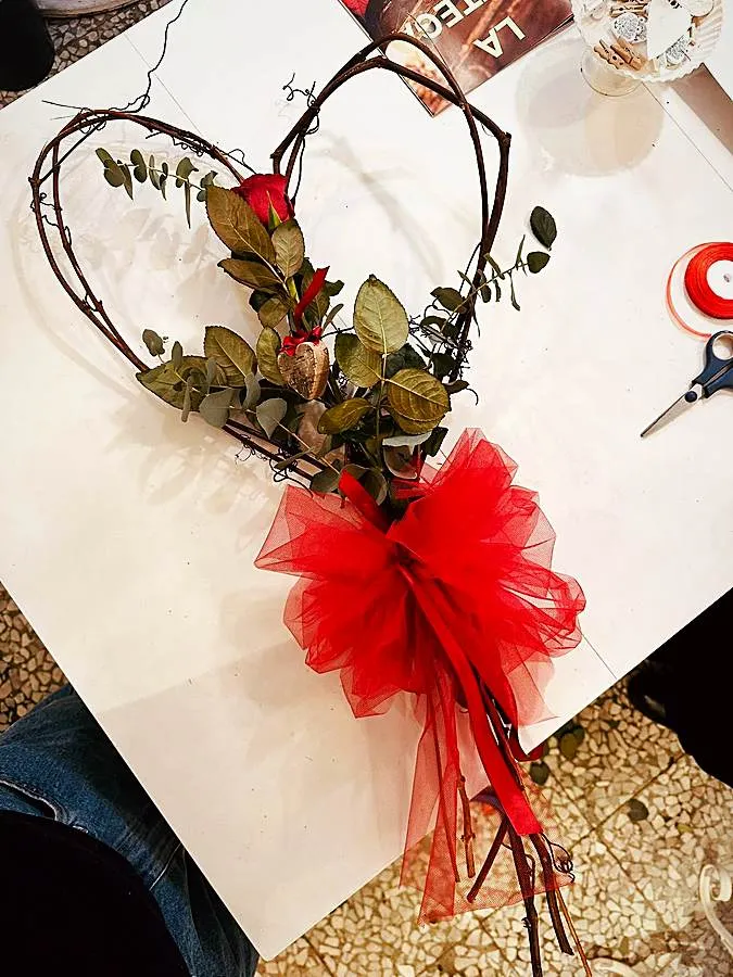 Cuore di rami intrecciati con rosa rossa, eucalipto e fiocco di tulle rosso