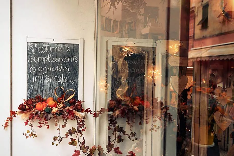 Ingresso della bottega in autunno, con lavagna e composizione di fiori secchi e zucche