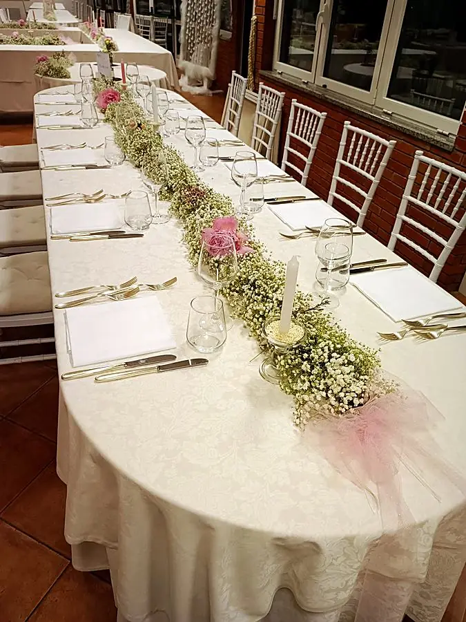 Lungo runner di gypsophila con peonie rosa su un tavolo apparecchiato, con fiocco di tulle rosa