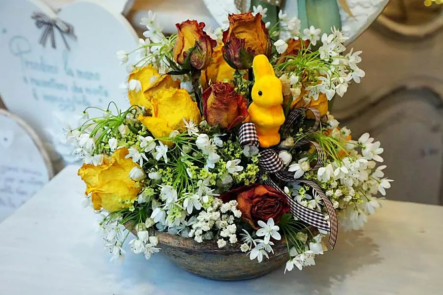 Rose gialle essiccate, fiorellini bianchi e coniglietto giallo in una ciotola