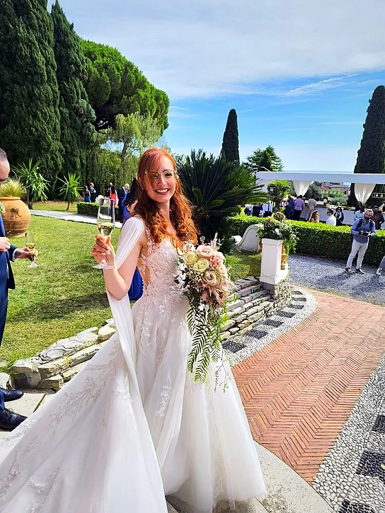 Sposa in giardino con bouquet di rose rosa e cipria, erba delle pampas e rametti pendenti