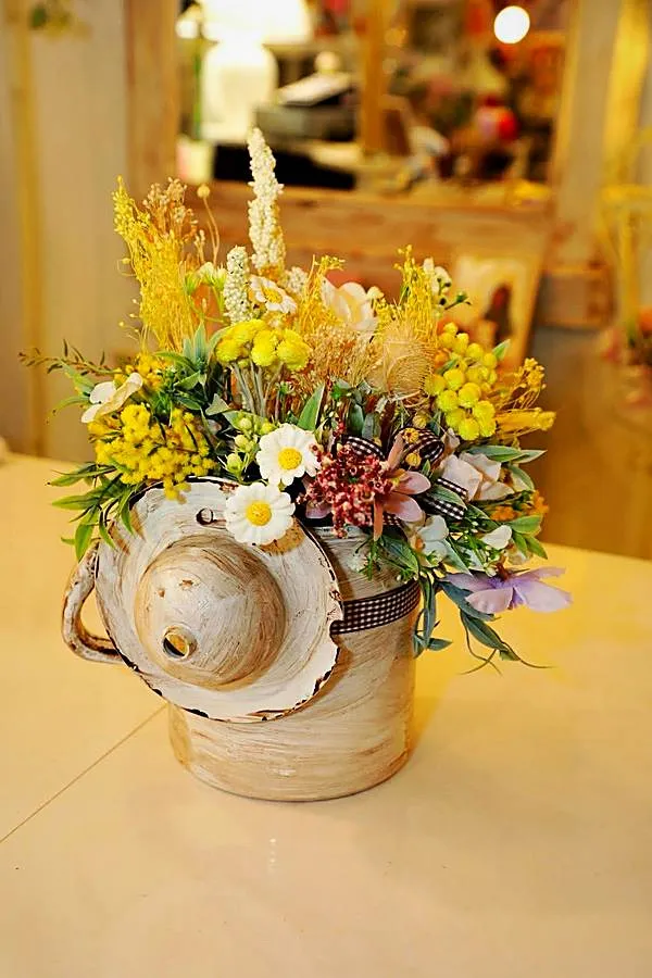Vaso vintage con mimosa, margherite e fiori secchi gialli e nastro a quadretti